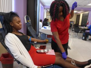 Simone Scott (left), KPMG, after making her donation, gets support from Nurse Latoya Pusey.