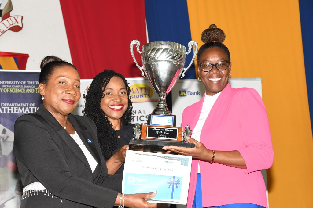 Sandra Jones (left), Manager of Public Sector Engagement at JN Bank and Hon. Marsha Smith (centre), Minister of State in the Ministry of Education and Youth (MOEY), present Cameka Ingram (right) of Green Pond Primary in St James with her winning trophy and cash award