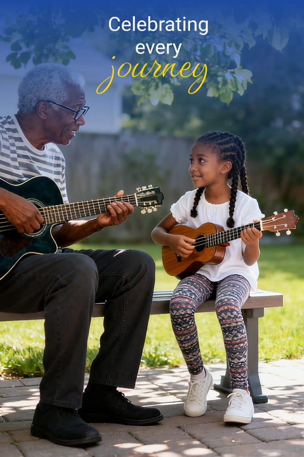 Grandfather and young girl playing guitars on a park bench outdoors, sharing a smile; overlay text reads "Celebrating every journey".